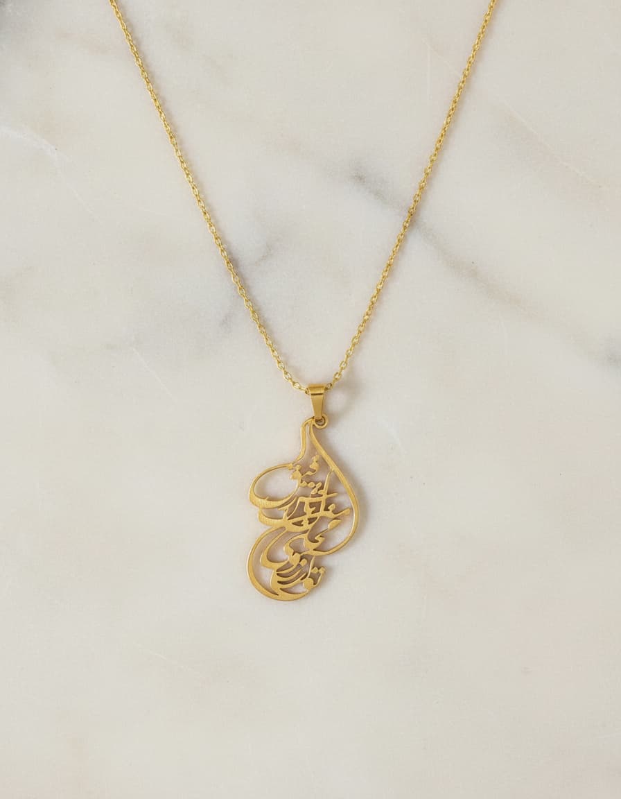 Gold-plated Persian calligraphy pendant necklace on marble