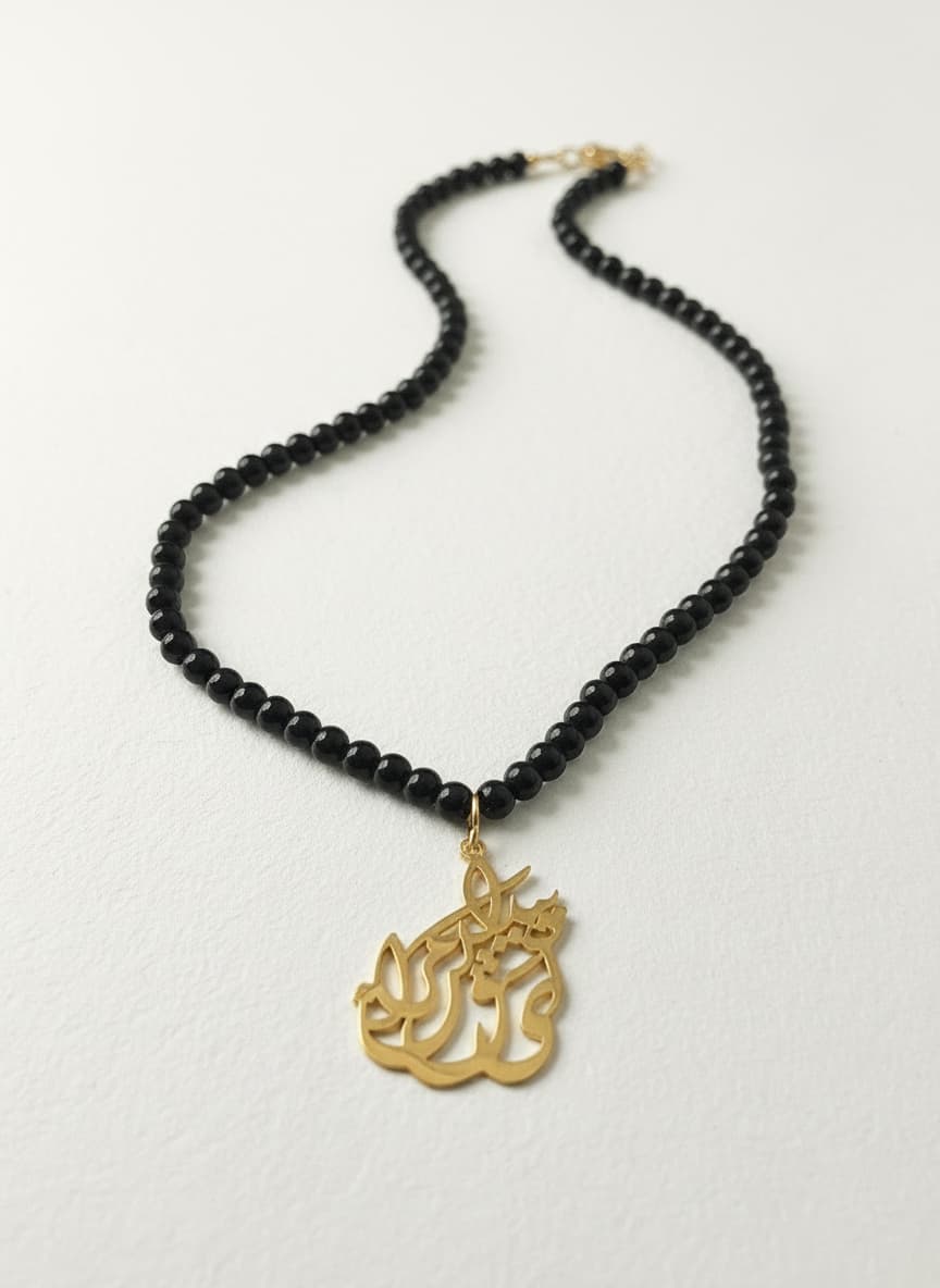 Gold-plated calligraphy pendant necklace with onyx beads on white