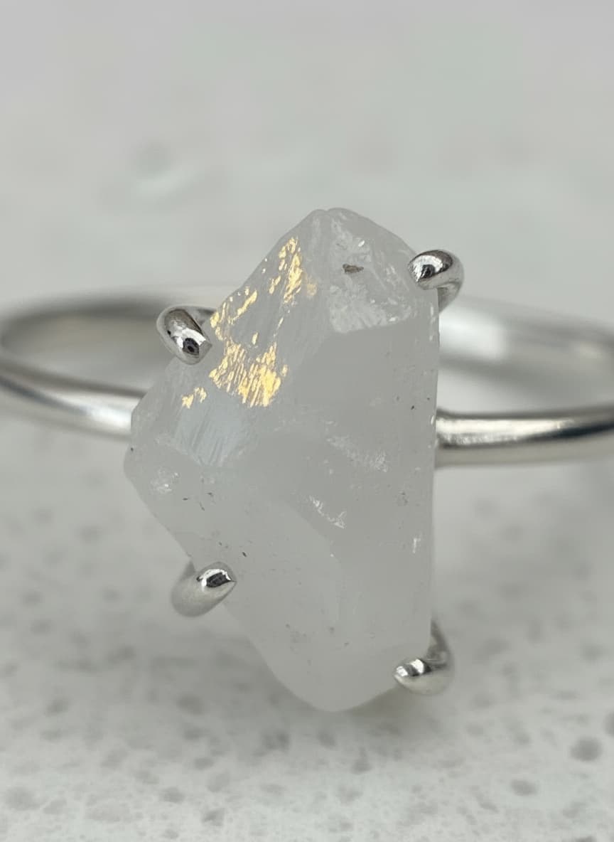 White stone ring styled with a pearl-like pendant necklace, silver-tone earrings and an open cuff bracelet.