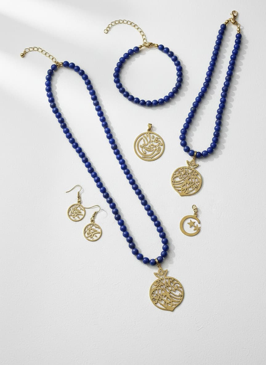 Gold-plated calligraphy pomegranate necklace styled in a flatlay with sapphire jewelry