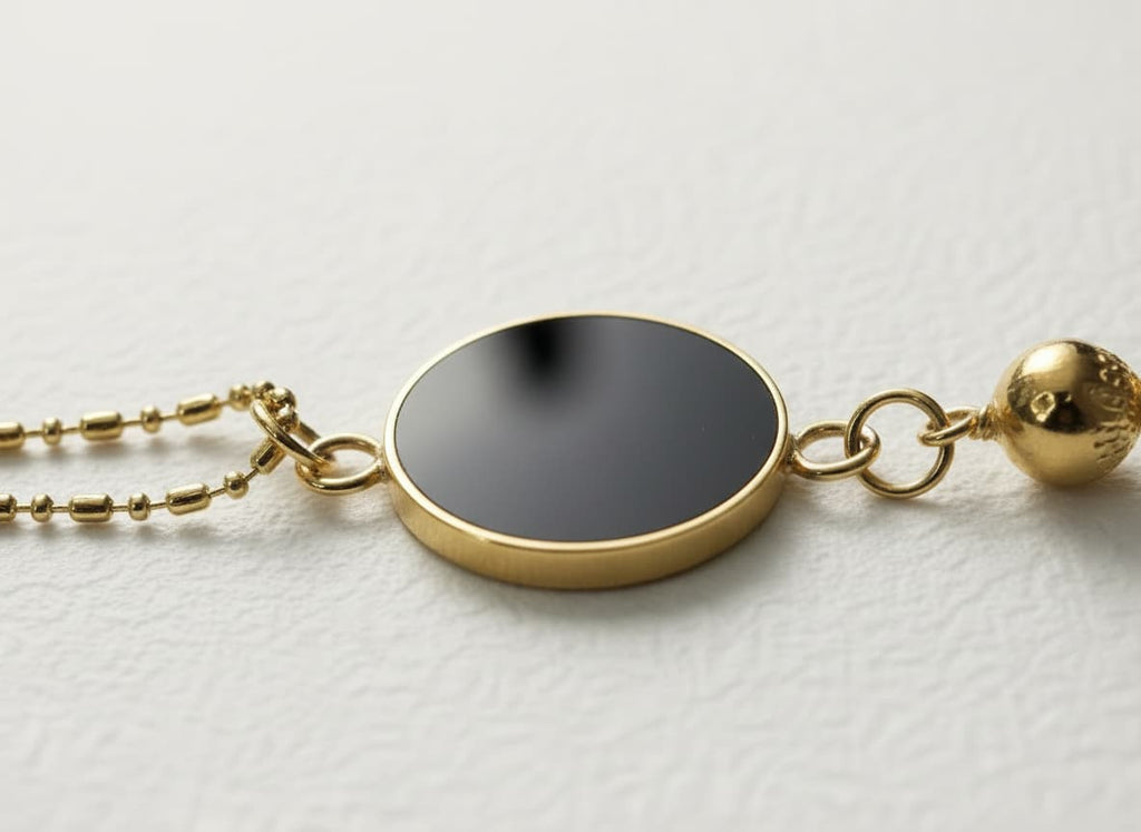 Macro close-up of the black enamel disc and pomegranate charm