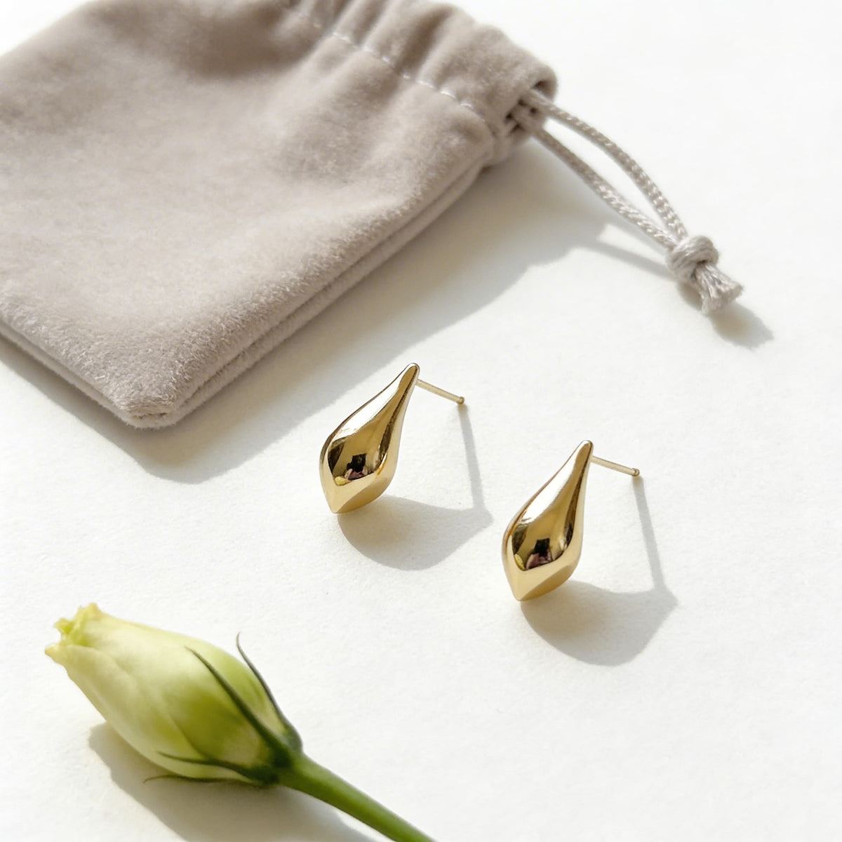 Gold teardrop earrings styled with velvet pouch