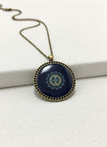 Brass bird and water medallion necklace on white