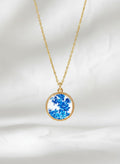 Gold ceramic necklace with blue and white floral design on white