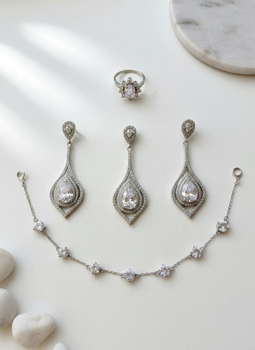 Silver-plated teardrop earrings styled in a flatlay with silver jewelry