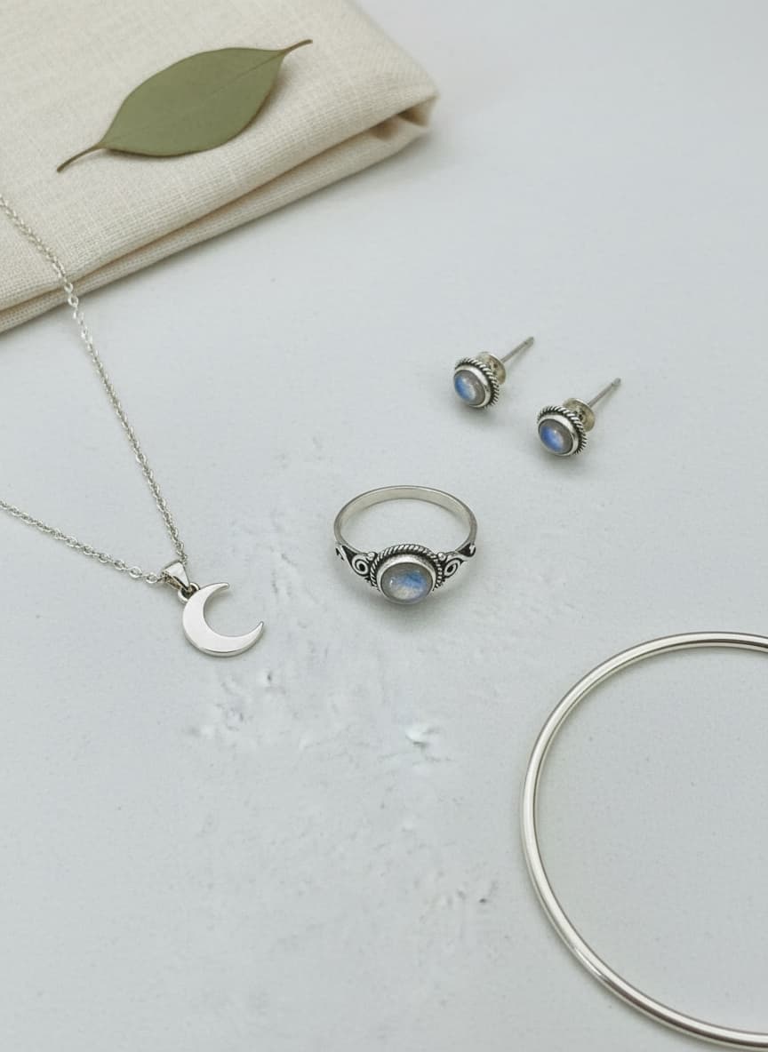 Silver moonstone ring styled in a flatlay with moon necklace and earrings