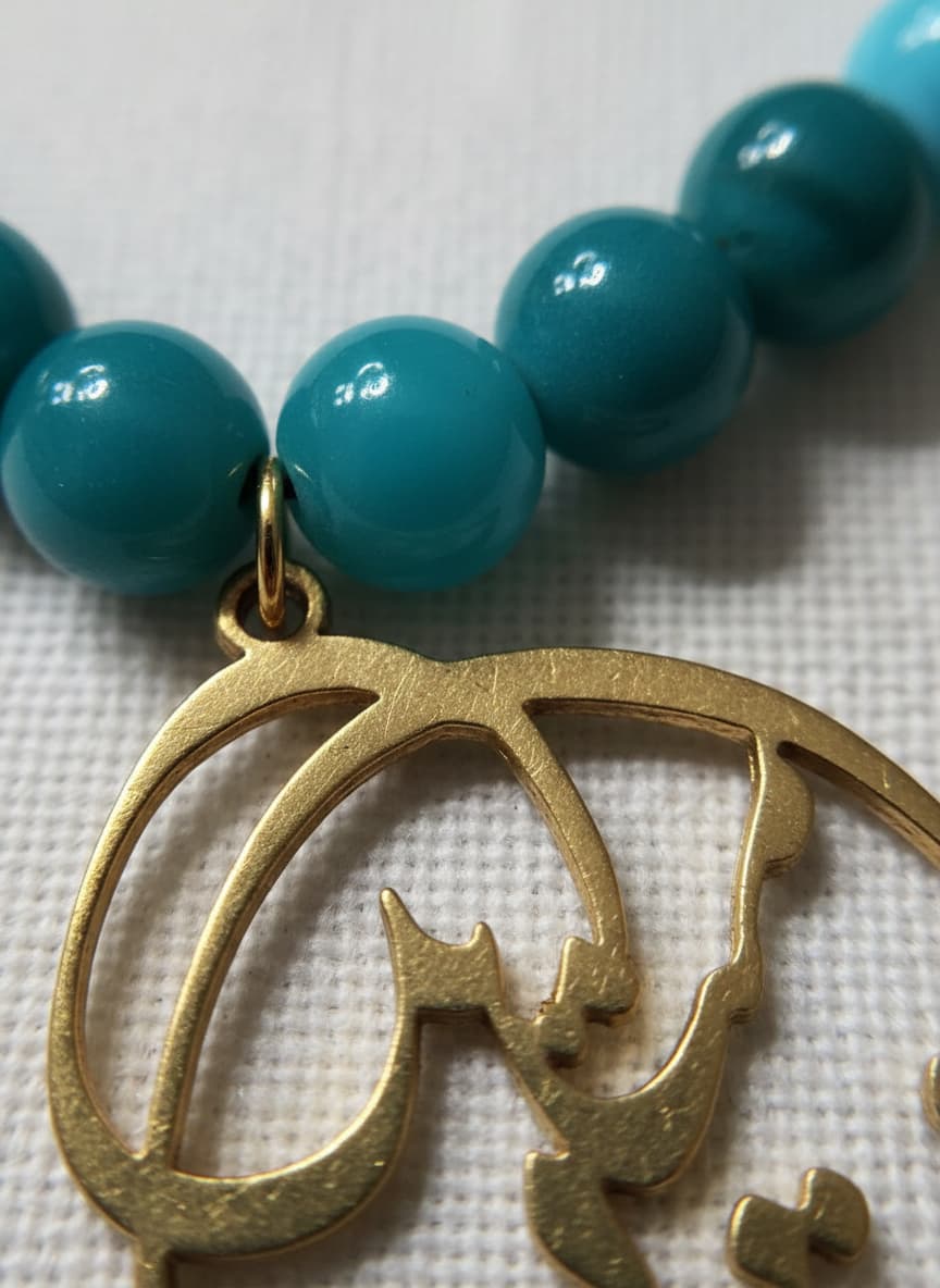 Macro close-up of the gold calligraphy pendant