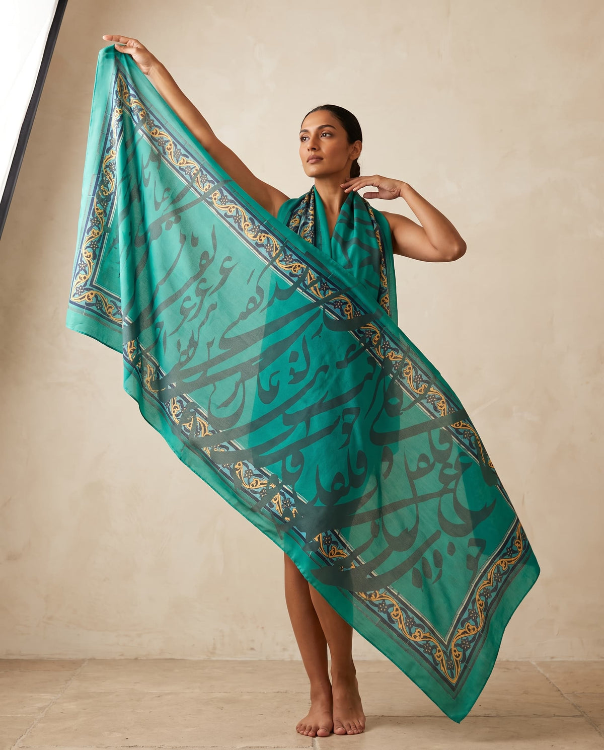 Model wearing a teal shawl with large Persian calligraphy
