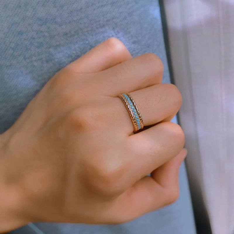 Hand wearing rose gold ring with turquoise stones