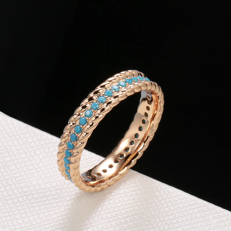 Rose gold ring with turquoise stones on a white surface