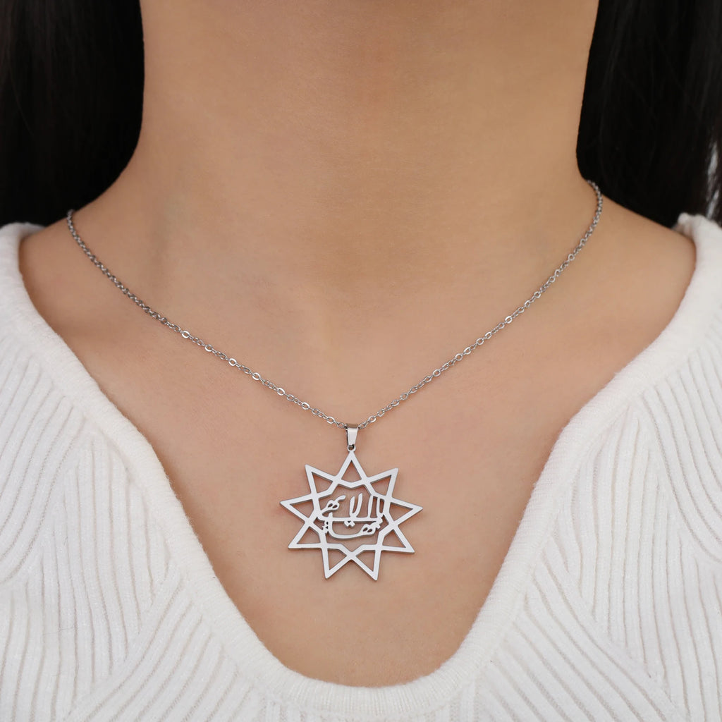 Silver star-shaped pendant necklace on a person wearing a white sweater