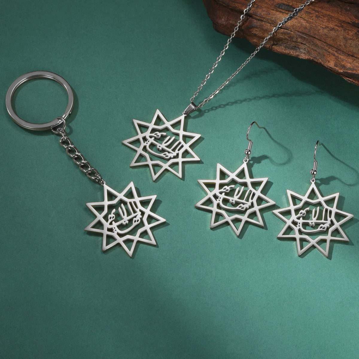 Silver star-shaped jewelry set including a keychain, necklace, and earrings on a green background.