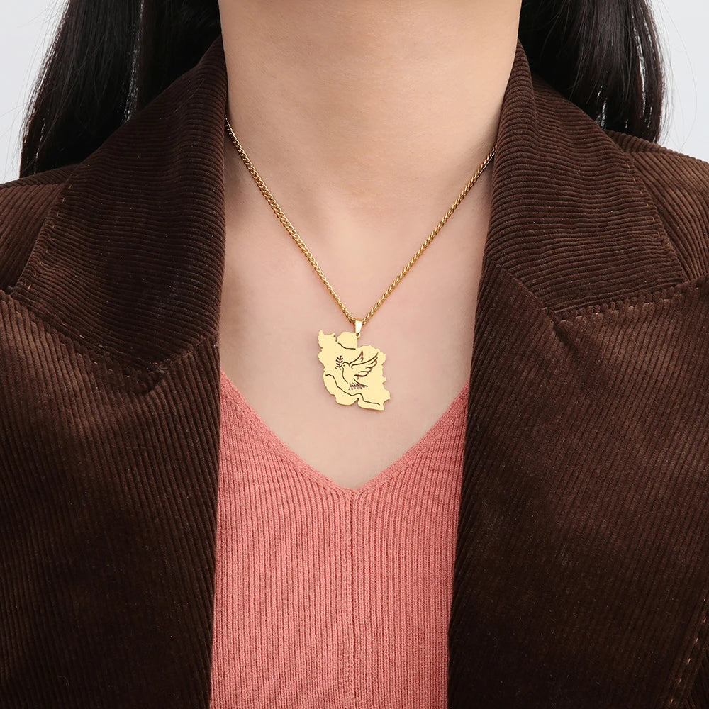 A close-up of a person wearing a gold pendant necklace with a bird design, styled with a brown corduroy jacket and a pink ribbed top.