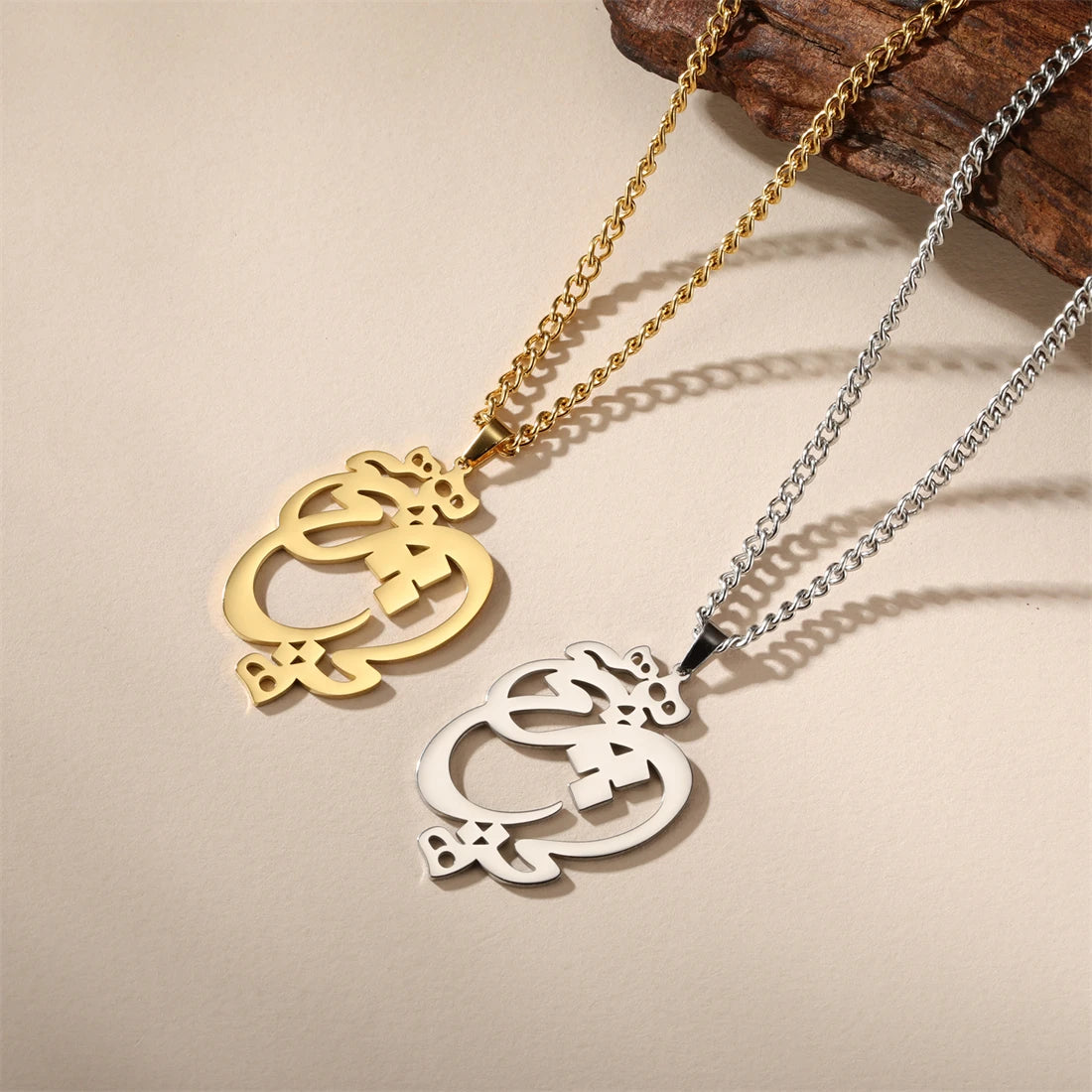 Gold and silver pendants on chains against a beige background