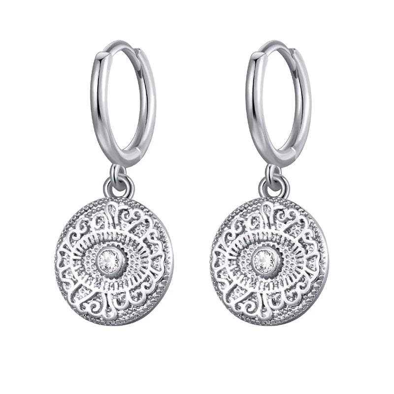 Silver hoop earrings with circular dangling charms on a white background