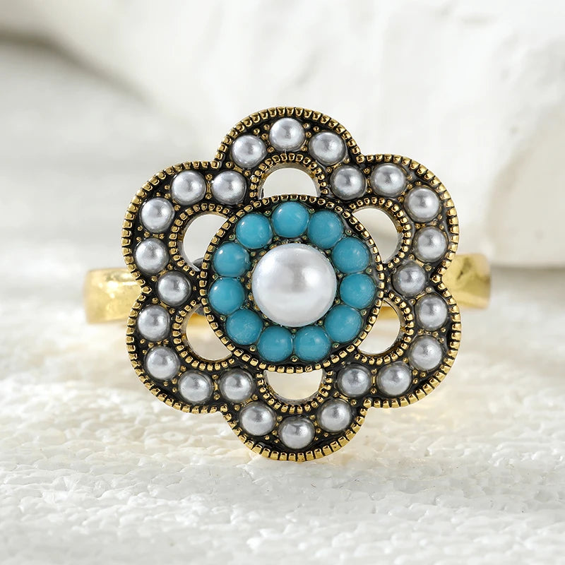 Decorative ring with turquoise and pearl design on a textured white background