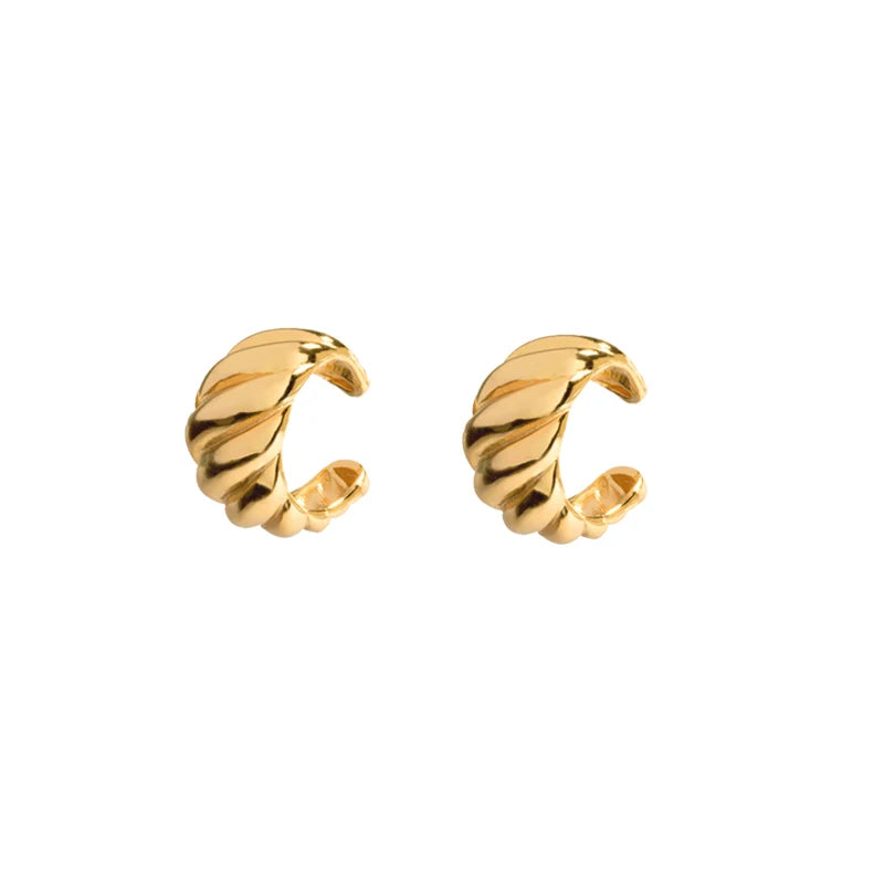 A pair of gold-toned twisted huggie hoop earrings on a plain white background.
