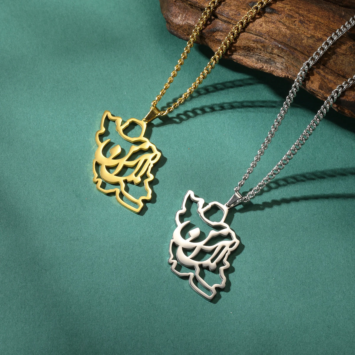 Two leaf-shaped pendants on gold and silver chains against a green background