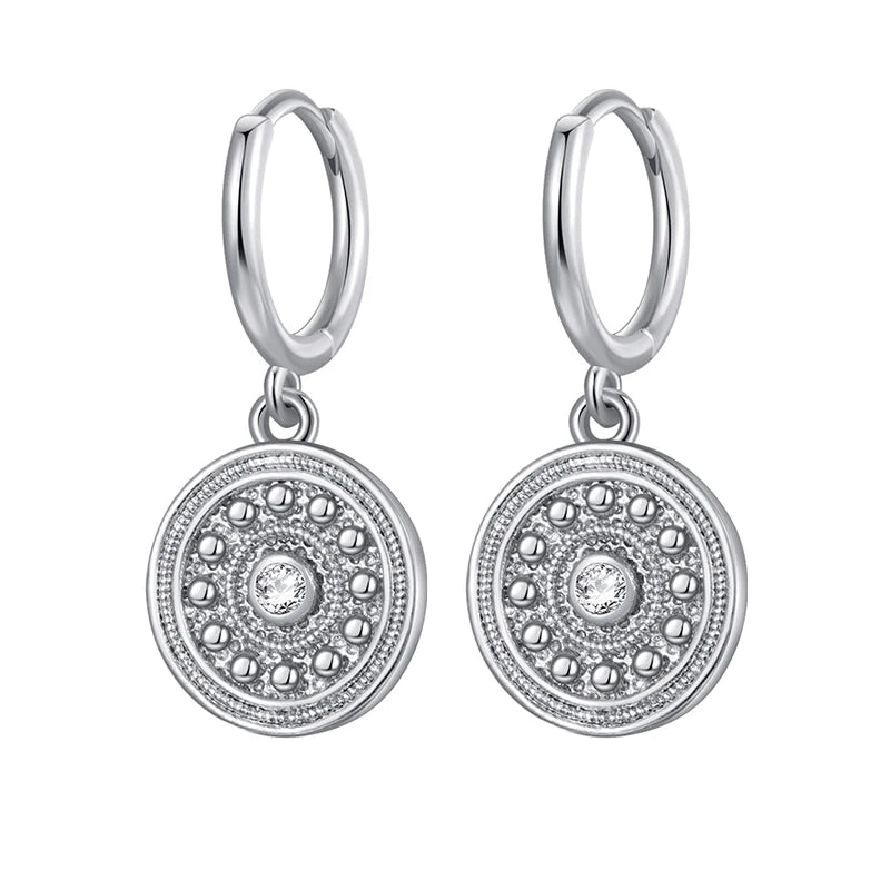 Silver hoop earrings with circular dangling charms on a white background