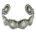Silver-toned cuff bracelet with sunburst filigree medallions on white background