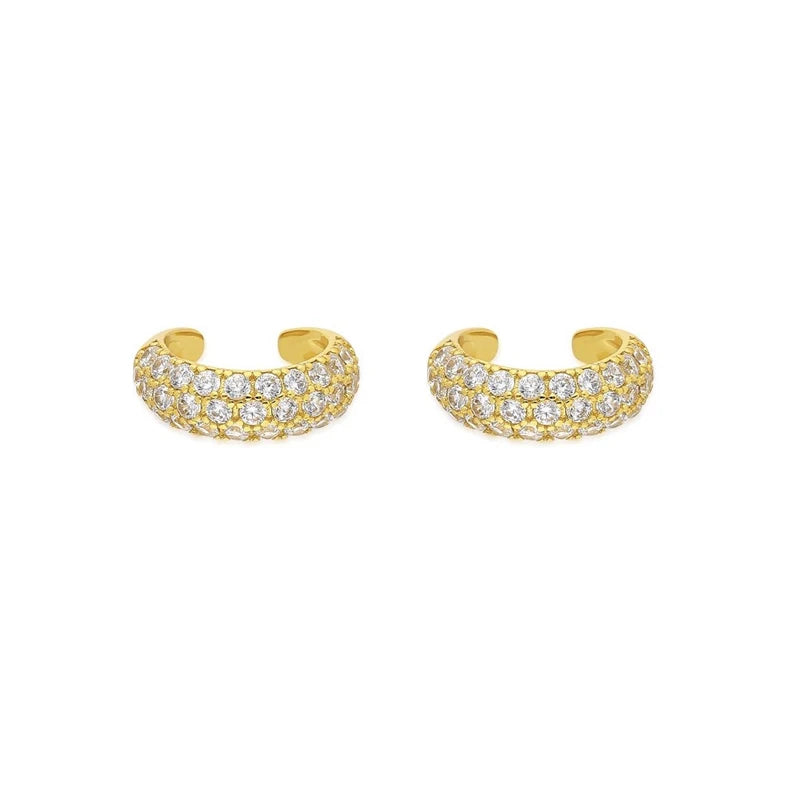 A pair of gold huggie hoop earrings paved with small clear cubic zirconia stones, displayed on a clean white background.