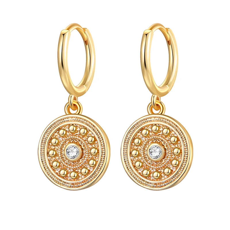 Gold hoop earrings with circular designs and small stones on a white background
