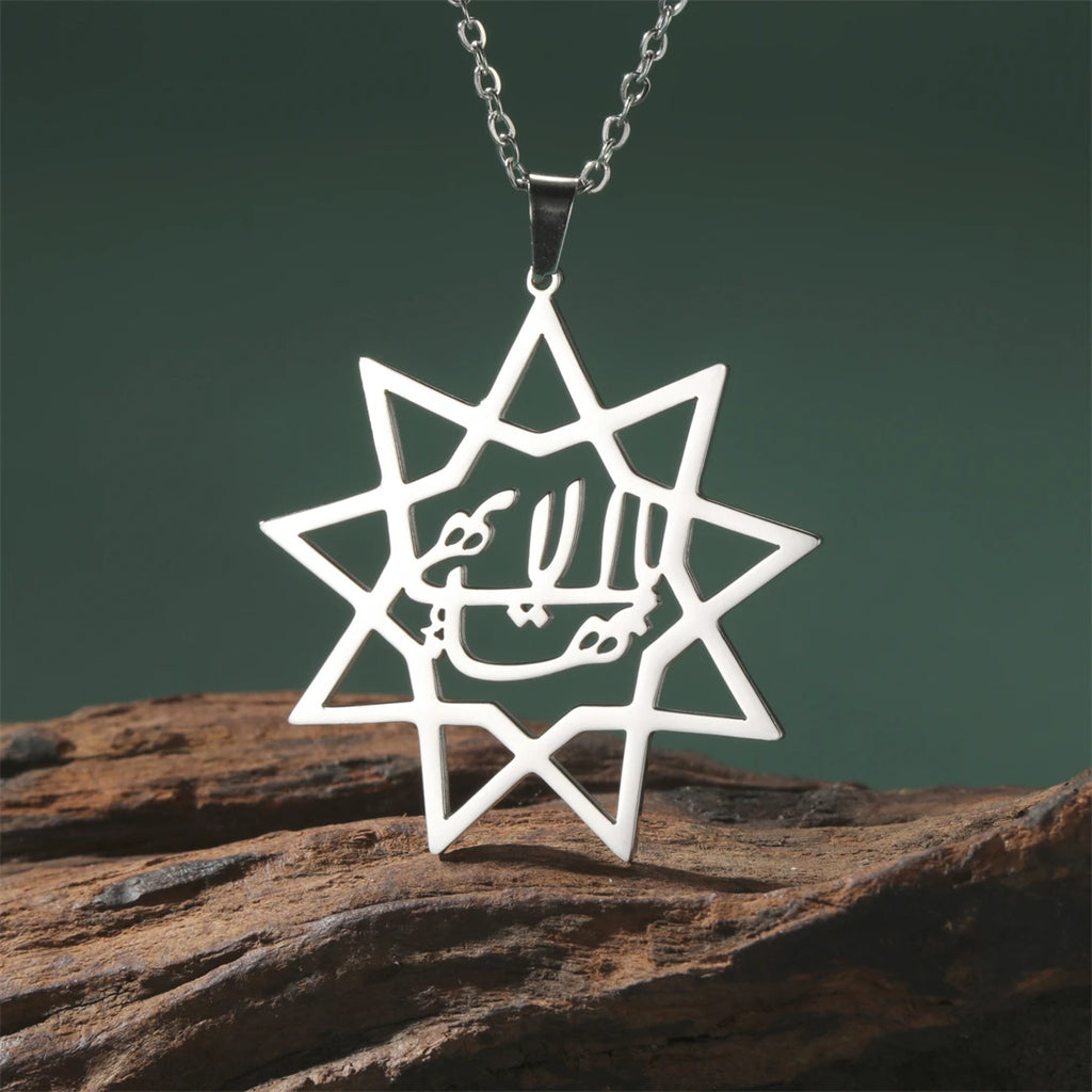 Star-shaped pendant with Arabic text on a chain, placed on a wooden surface with a dark green background.