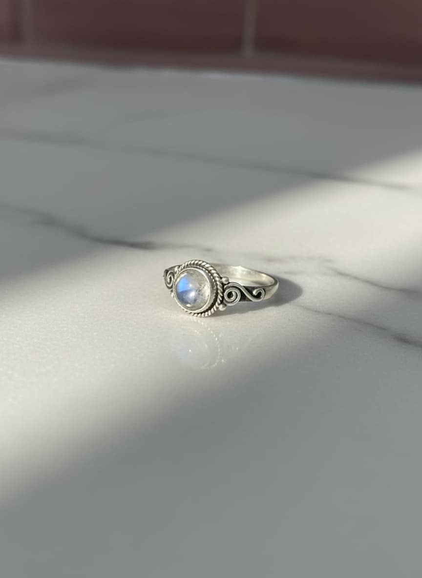 Silver moonstone ring on marble in sunlight