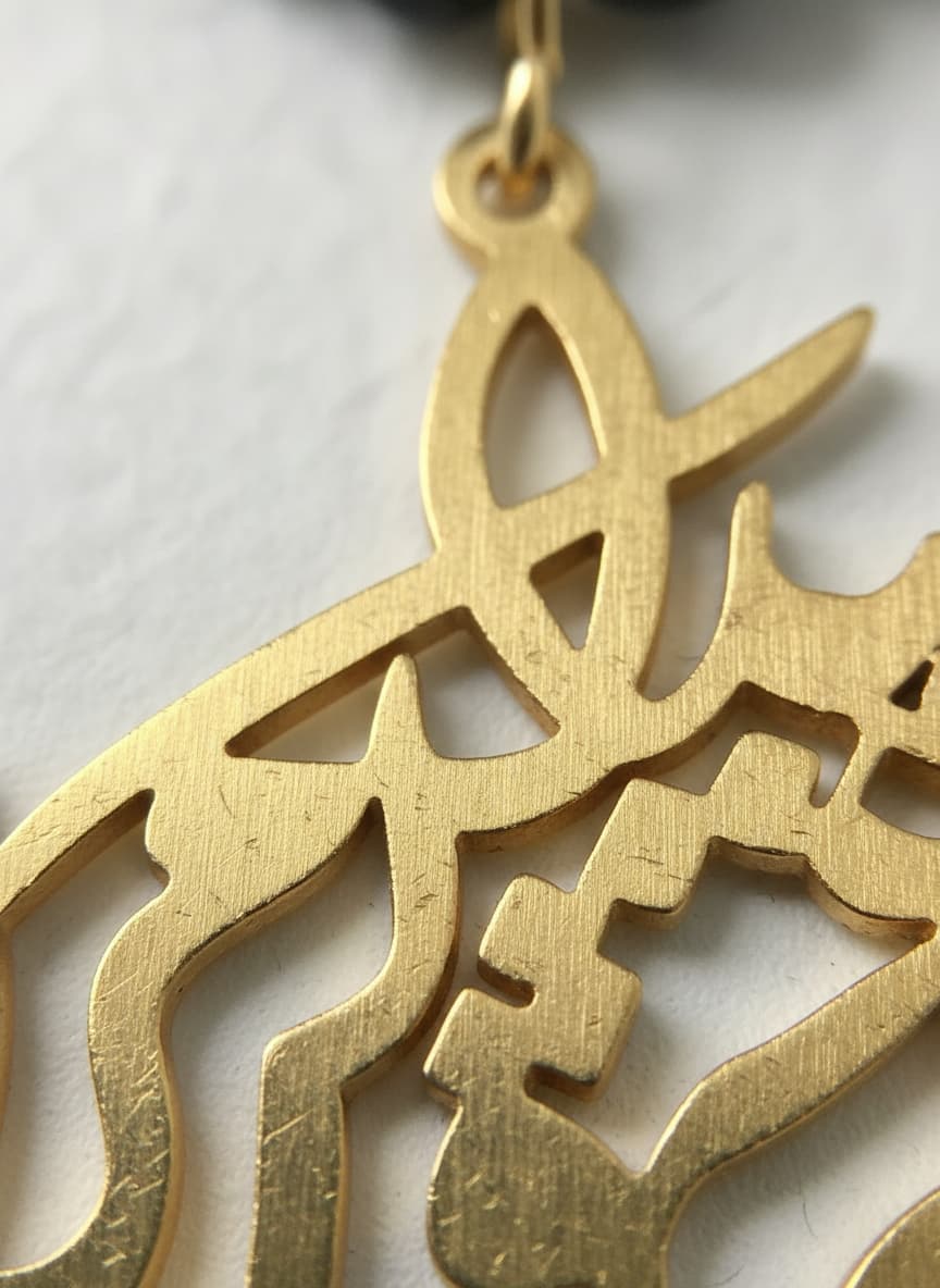 Macro close-up of the gold-plated calligraphy pendant and onyx beads