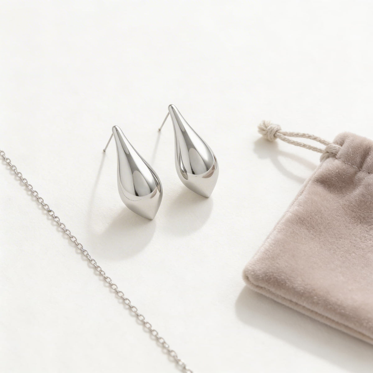 Silver teardrop earrings styled with chain and velvet pouch