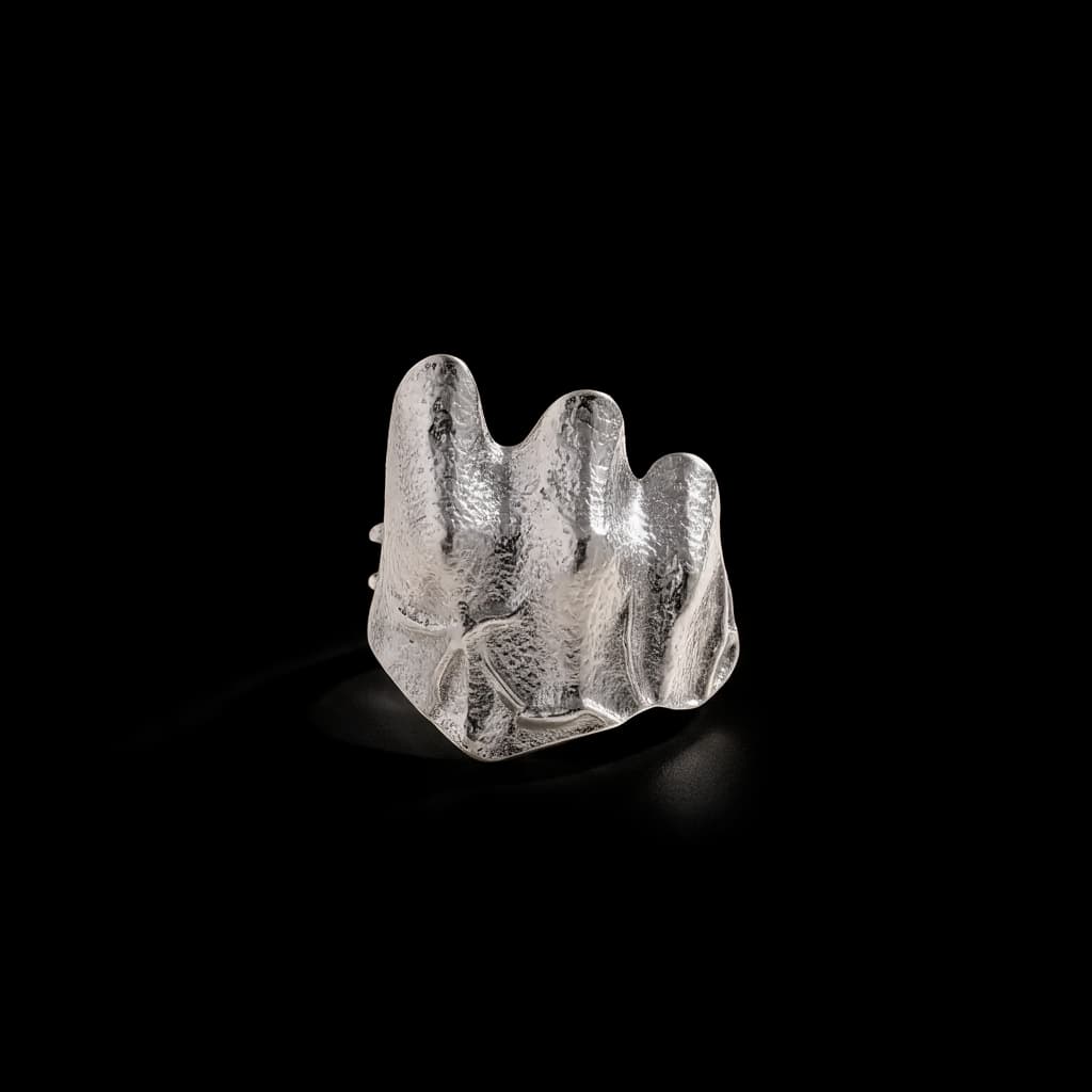 Silver-tone hammered statement ring on black background