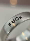 Macro close-up of the engraved lettering on the silver band ring