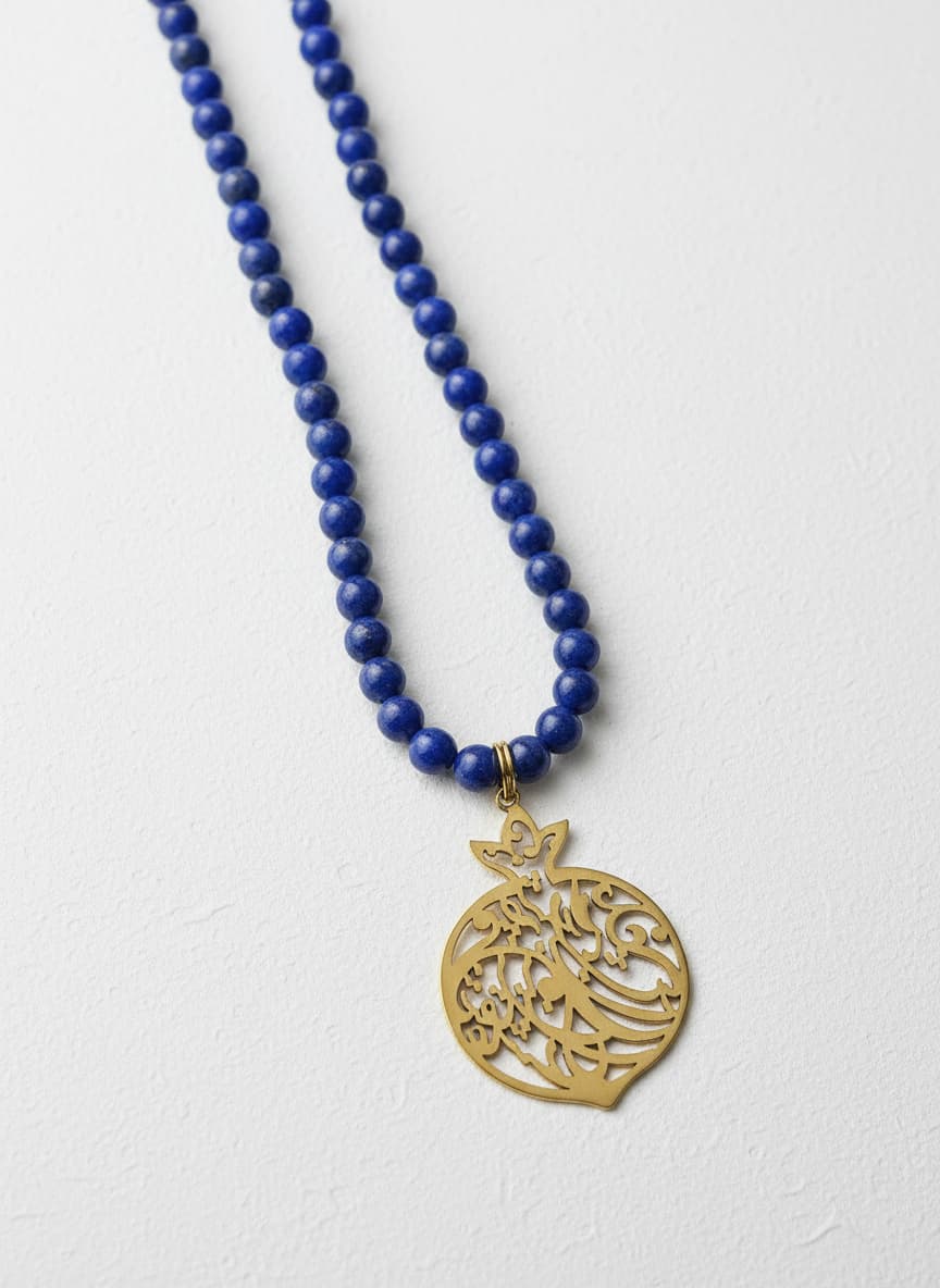Gold-plated calligraphy pomegranate necklace with sapphire beads on white