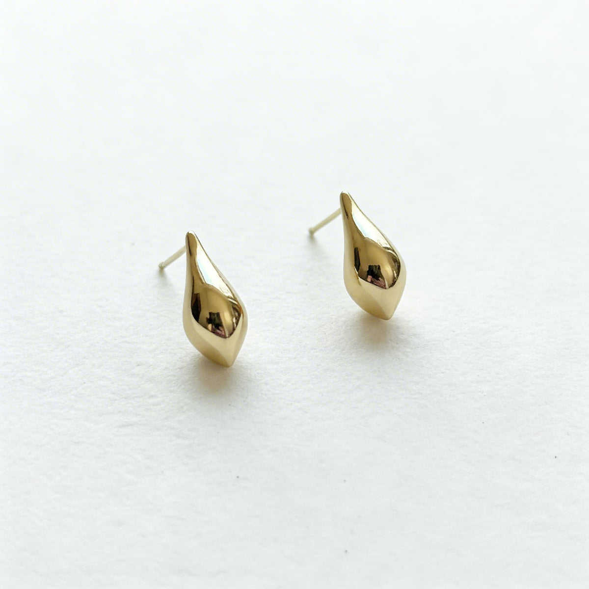 Gold teardrop hanging earrings on white