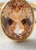 Macro close-up of the champagne oval stone in the gold ring