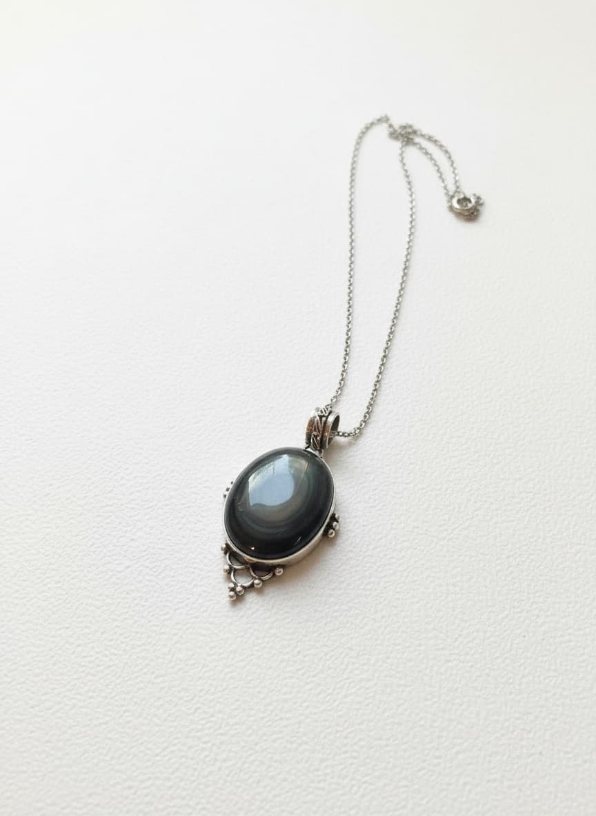 Deep banded agate cabochon pendant in ornate silver-tone filigree on a fine chain